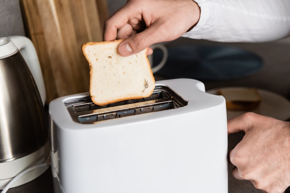 man putting sliced bread inside kitchen appliance