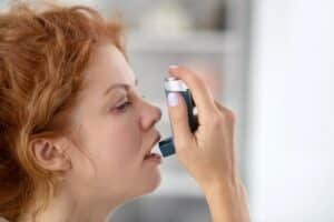 woman using inhalator while having an asthma attack