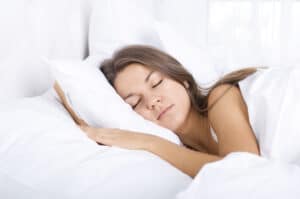 young woman sleeping on all-white bedding