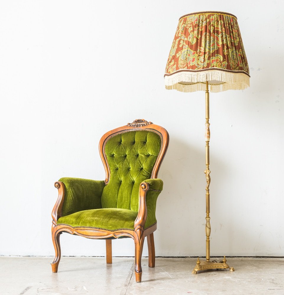 a green vintage sofa and floor lamp