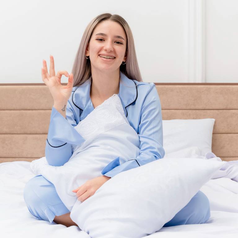 a lady in blue pajamas sitting on bed