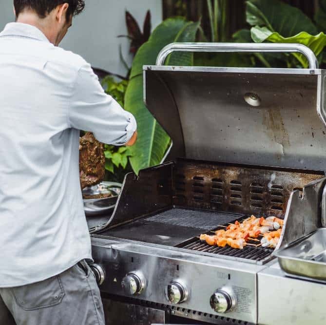 a man in tattoos makes barbecue grill meat outdoors