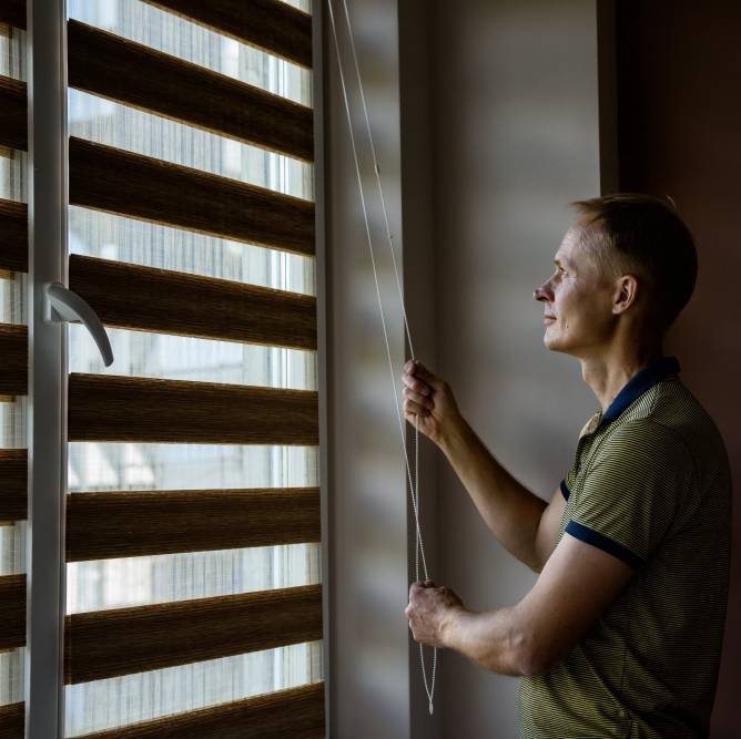 a man opening the blinders