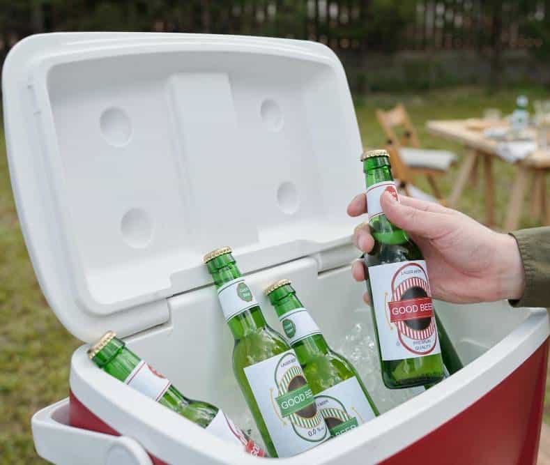 a man taking a bottle of beer out of a cool box