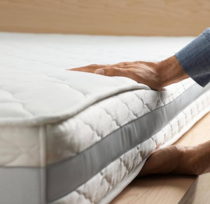 a man touching a soft white mattress