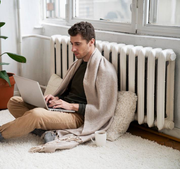 a man using a laptop near the heater