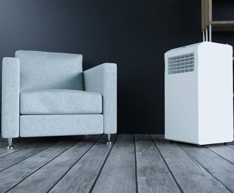 a mobile air conditioner next to a white armchair