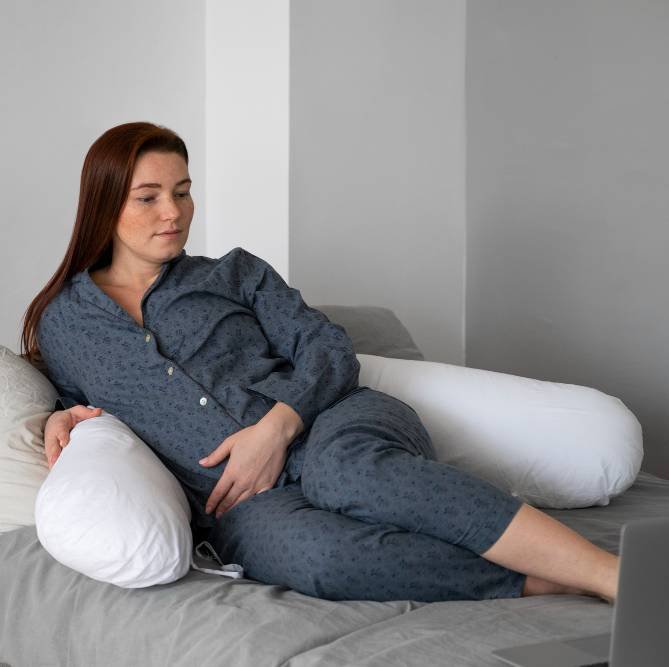 a pregnant woman sitting on a gray bed