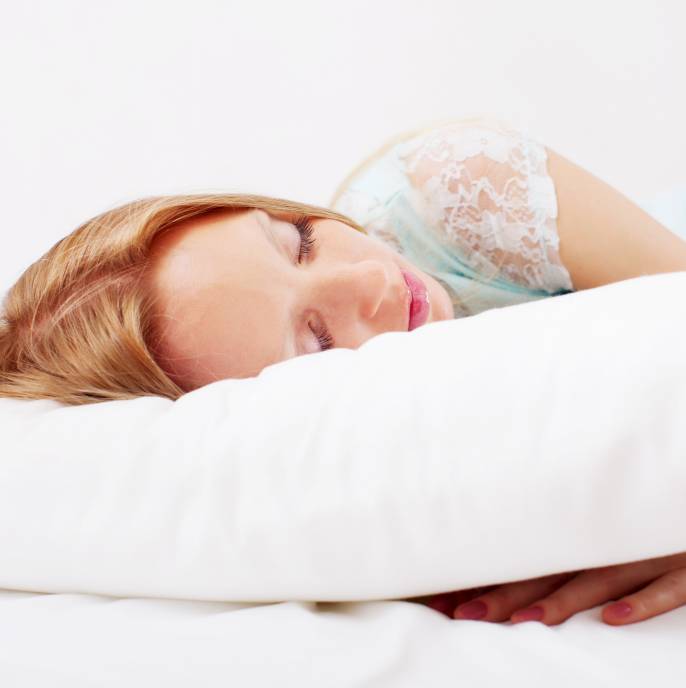 a woman in a nightshirt sleeping on a white pillow