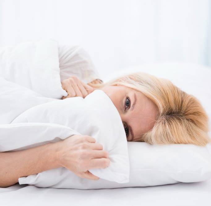 a woman lying on a bed with a smelly pillow
