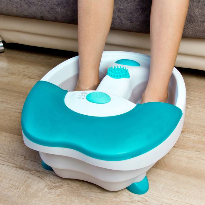 a woman using an electric foot spa massager