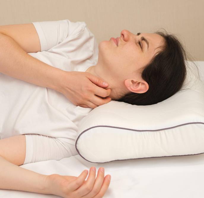a woman with neck pain after sleeping on a pillow