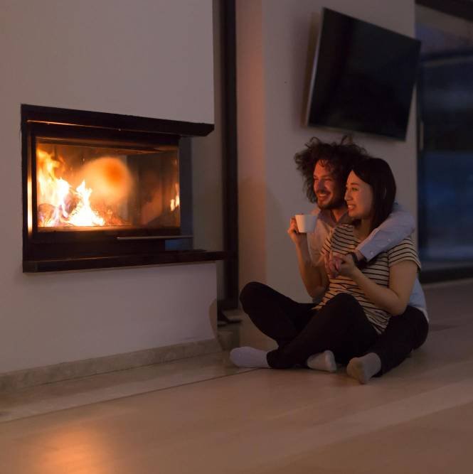 a young couple sitting on the floor in front of the fireplace