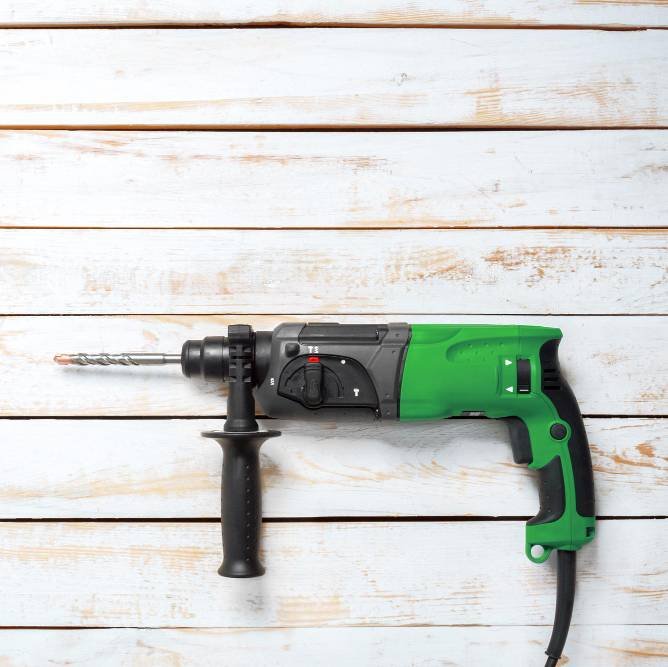 an electric hammer drill lying on a wooden table